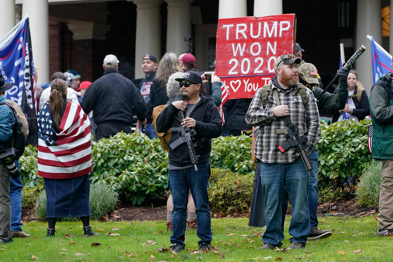 After breaching the gates around the Governor’s Mansion in Olympia, two men stand armed with guns in front of the residence, on Jan. 6, 2021, during a protest supporting President Donald Trump and against the counting of electoral votes in Washington, D.C., affirming President-elect Joe Biden’s victory. (Ted S. Warren /Associated Press file photo)
