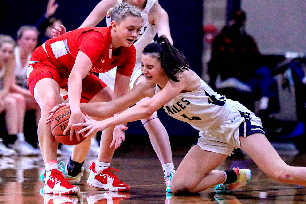 Arlington's Maddy Fischer, right, attempts a steal from Stanwood's Grace Walker at Arlington High School Saturday evening in Arlington, Washington on January 8, 2022. The Eagles won 57-47. (Kevin Clark / The Herald)
