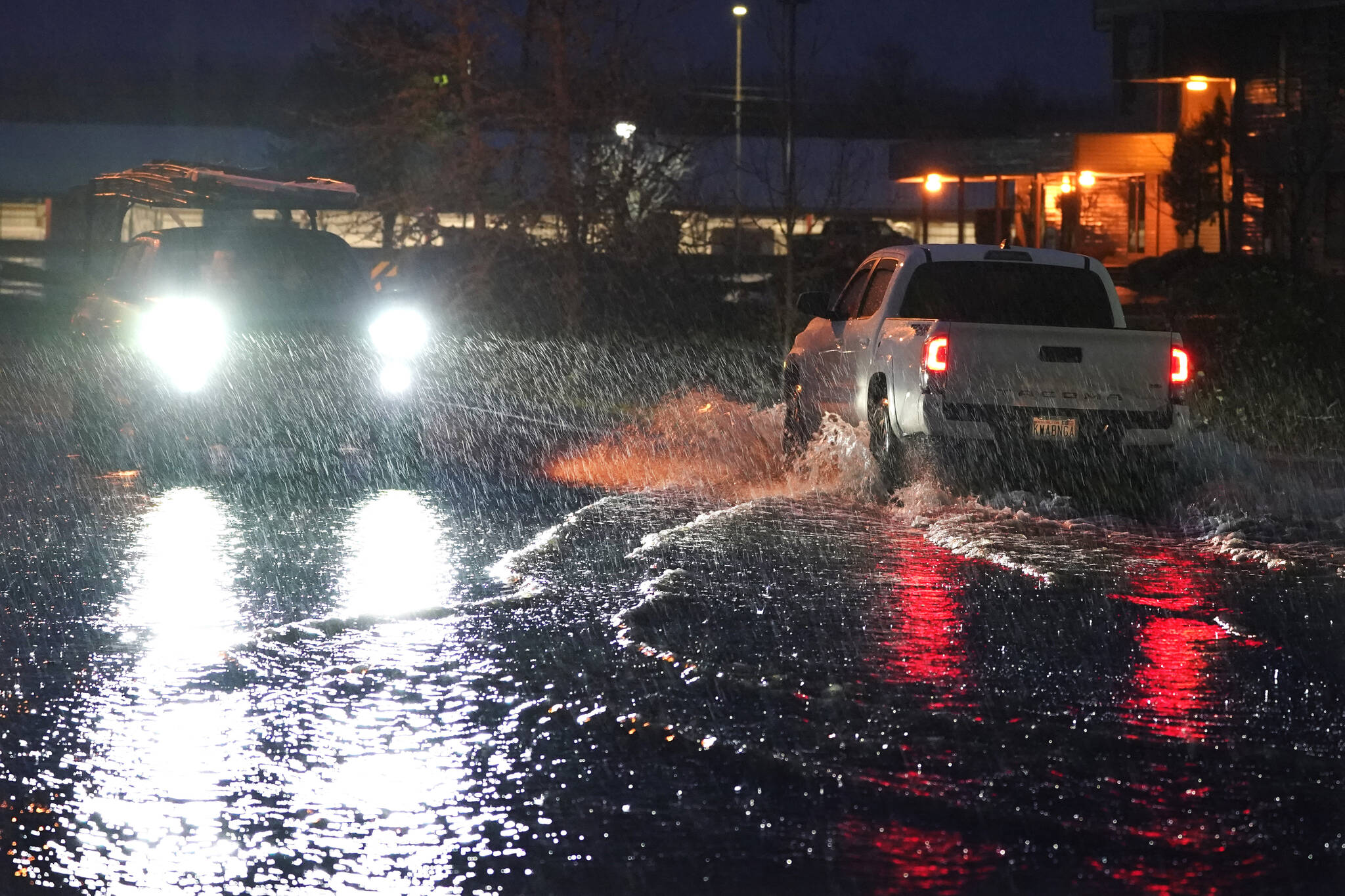 Vehicles drive through water over a street near NE Kresky Ave. in Centralia on Thursday. (AP Photo/Ted S. Warren)