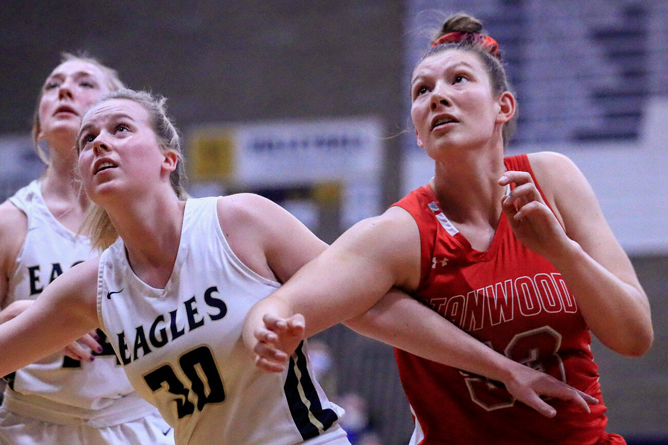 Arlington's Sophie Willis, left, and Stanwood's Vivienne Berrett look for a rebound at Arlington High School Saturday evening in Arlington, Washington on January 8, 2022. (Kevin Clark / The Herald)