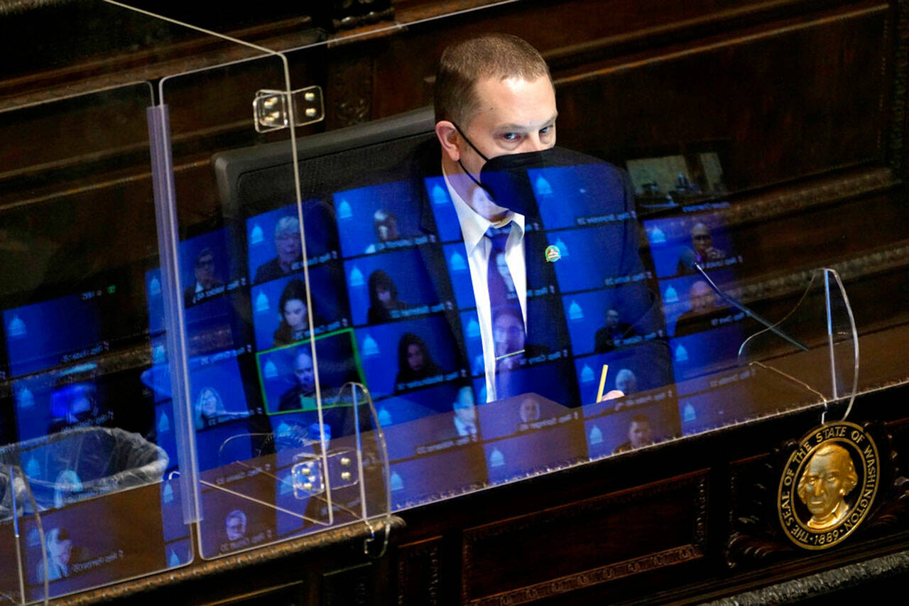 Gary Holt, who reads bills being considered in the Washington House, wears a mask as he sits behind a plexiglass shield with reflections of state representatives meeting remotely on it, April 21, 2021, at the Capitol in Olympia. As it did last year, much of the Legislature business will be conducted remotely during the 60-day session that began Monday. (Ted S. Warren / Associated Press file photo)