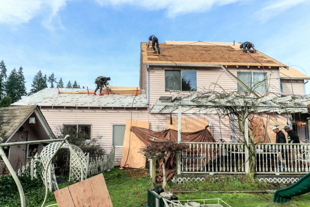 A local roofing company works to replace a deteriorating cedar-shingle roof as of the Home Repair Service Program Friday morning in Brier. (Kevin Clark / The Herald) 
