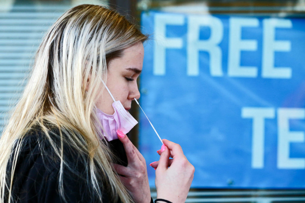 Sam Dawson administers a collection swab Thursday at the walk-up COVID testing center on Wetmore Avenue in Everett. (Kevin Clark / The Herald) 
