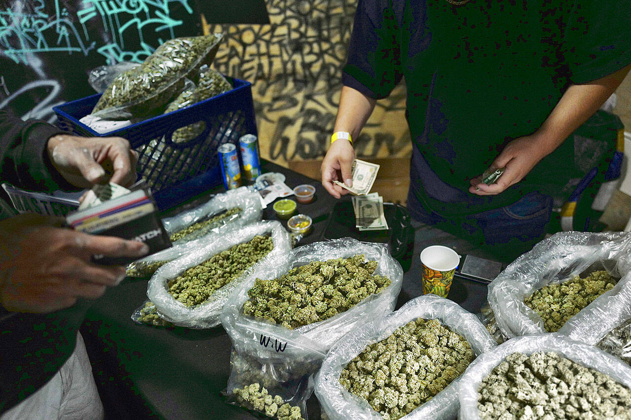 A vendor makes change for a customer April 15, 2019, at a cannabis marketplace in Los Angeles. An unwelcome trend is emerging in California, as the nation’s most populous state enters its fifth year of broad legal marijuana sales. Industry experts say a growing number of license holders are secretly operating in the illegal market — working both sides of the economy to make ends meet. (AP Photo/Richard Vogel, File)