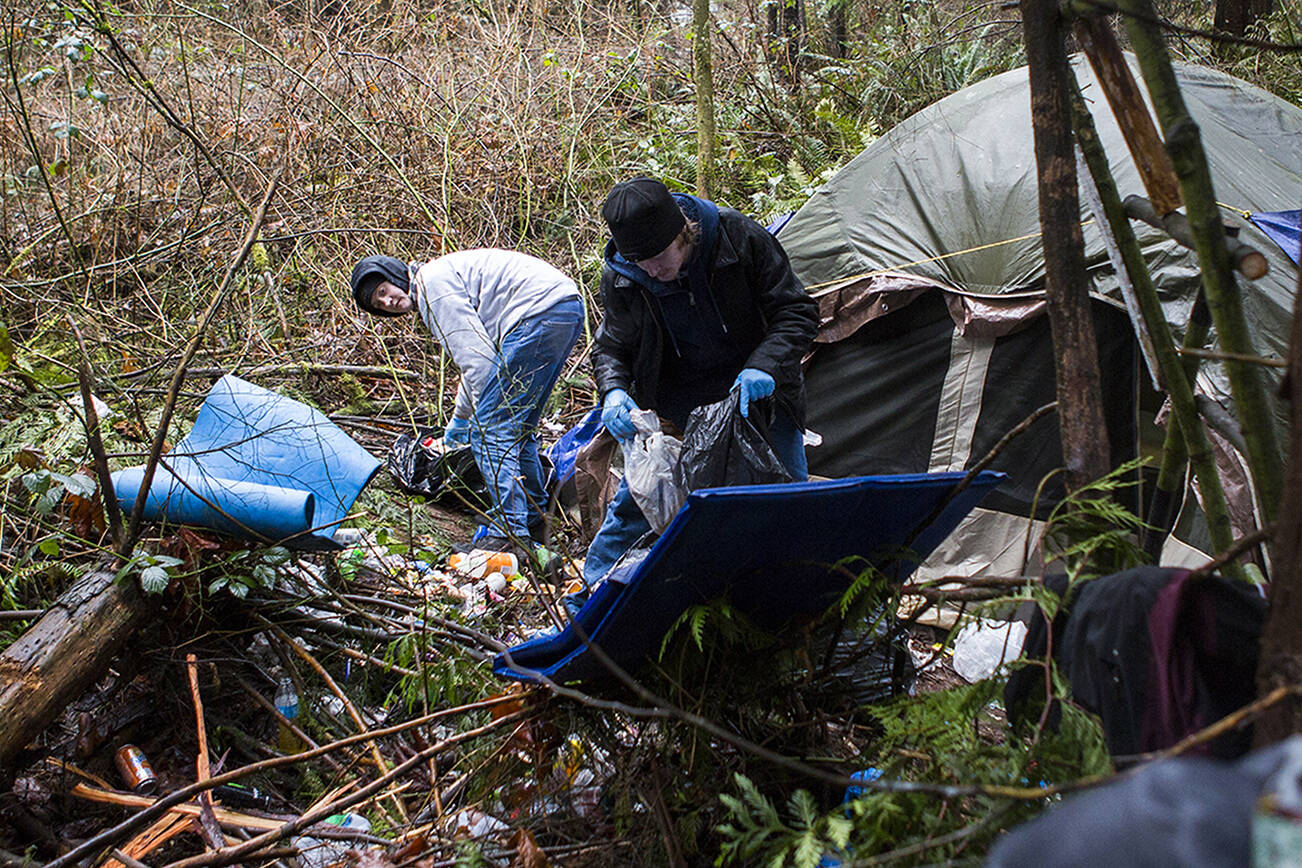Michael Jensen, left, and Nathan Jensen, right, pick up trash in their encampment that they being forced to clear out of by Parks Department the near Silver Lake on Wednesday, Jan. 23, 2019 in Everett, Wa. (Olivia Vanni / The Herald)