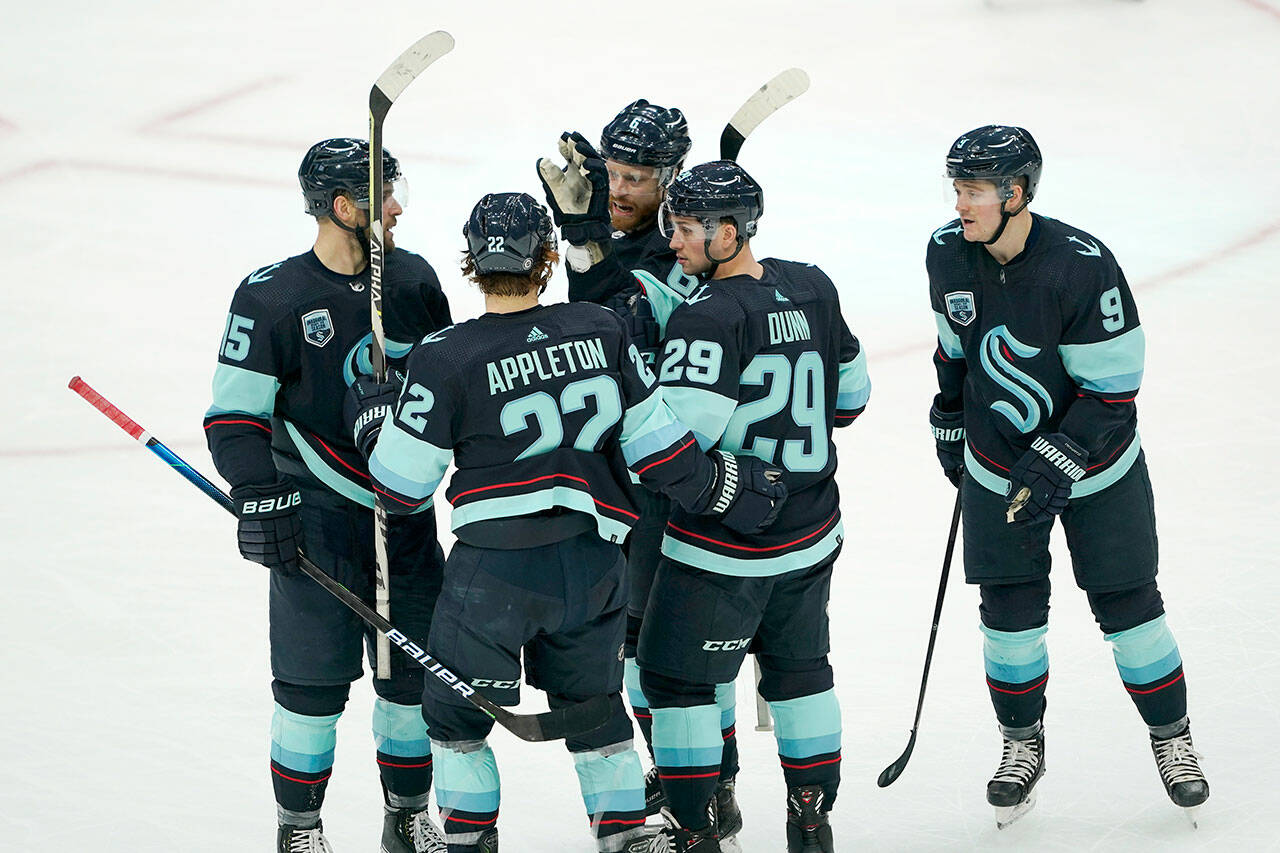 Seattle Kraken defenseman Vince Dunn (29) is greeted by teammates after he scored a goal against the Chicago Blackhawks during the second period of a game Monday in Seattle. (AP Photo/Ted S. Warren)