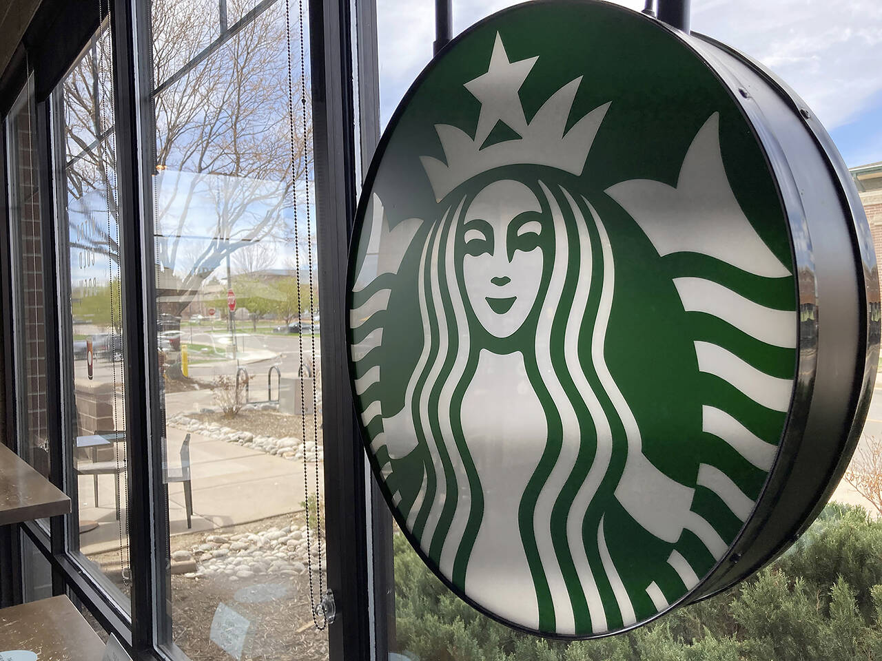 A sign bearing the corporate logo hangs in the window of a Starbucks open only to take-away customers in this photograph taken April 26, 2021, in southeast Denver. (AP Photo/David Zalubowski, file)