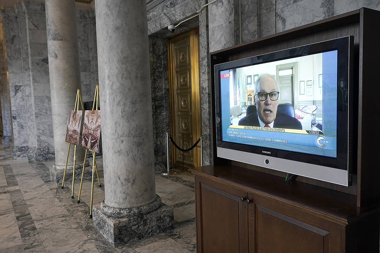 Washington Gov. Jay Inslee is shown on a video monitor outside the Senate chamber as he testifies remotely at a committee hearing on a bill that would make it a gross misdemeanor for elected officials or candidates to knowingly lie about election outcomes if those claims result in violence, Friday, Jan. 28, 2022, at the Capitol in Olympia, Wash. (AP Photo/Ted S. Warren)