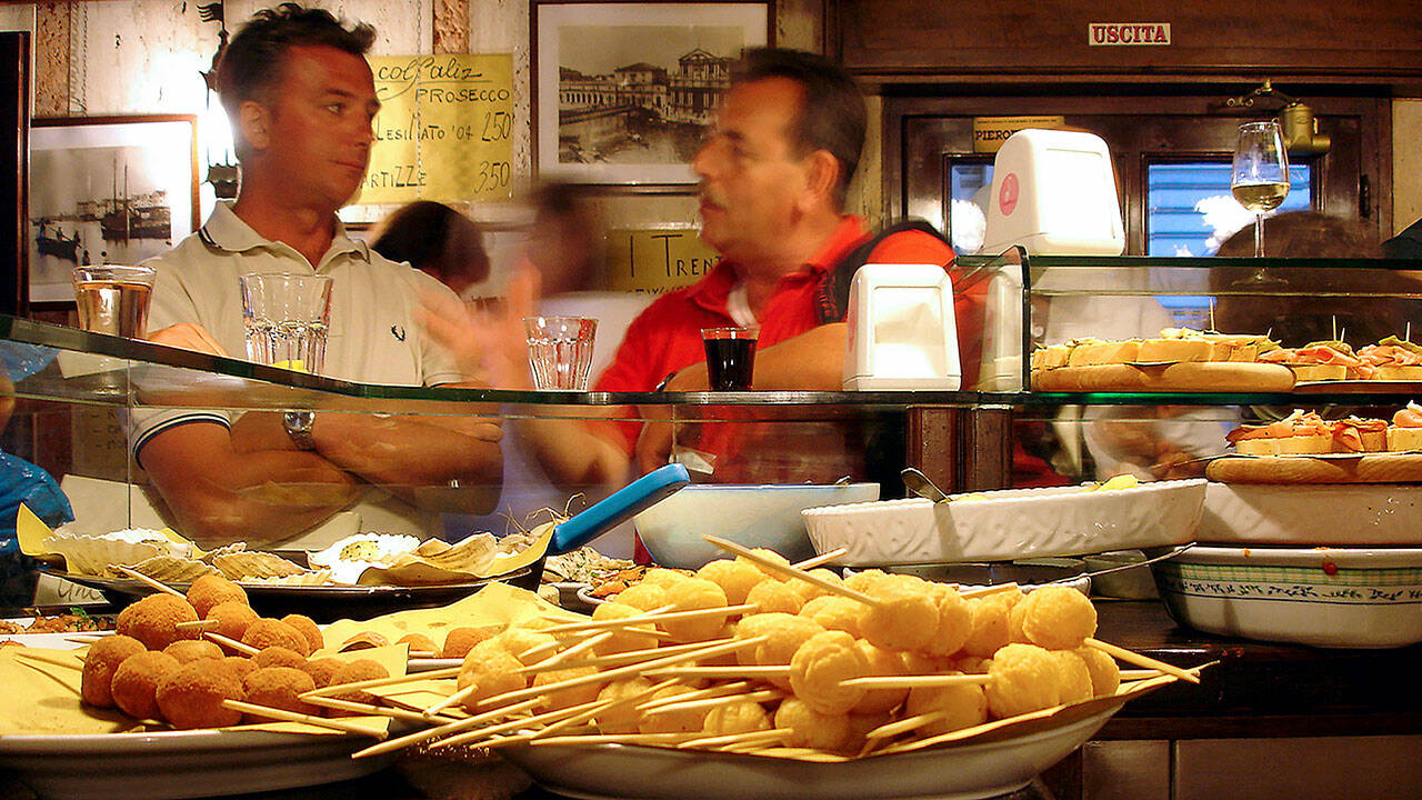 Diners sample an assortment of Venetian munchies at a cicchetti bar. (Rick Steves’ Europe)