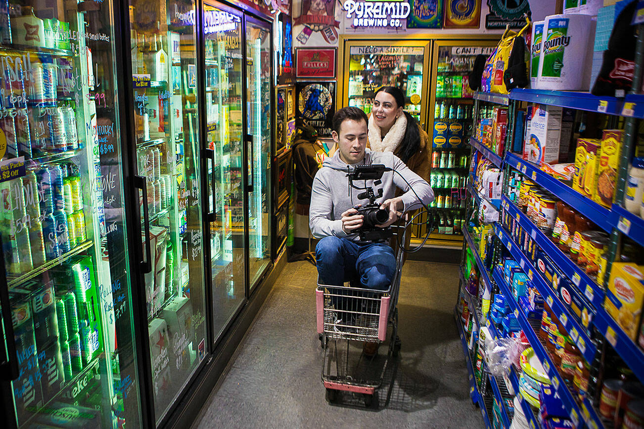 Director, producer and writer Rosie Kreider and cinematographer Barry J. Briggs make their way down an isle inside Norm's Market where they filmed for their upcoming movie on Thursday, Jan. 27, 2022 in Lake Stevens, Washington. (Olivia Vanni / The Herald)