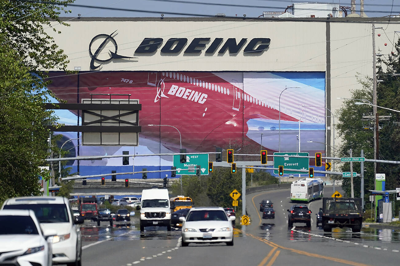 Traffic drives in view of a massive Boeing Co. production plant, where images of jets decorate the hangar doors, Friday, April 23, 2021, in Everett, Wash. (AP Photo/Elaine Thompson)