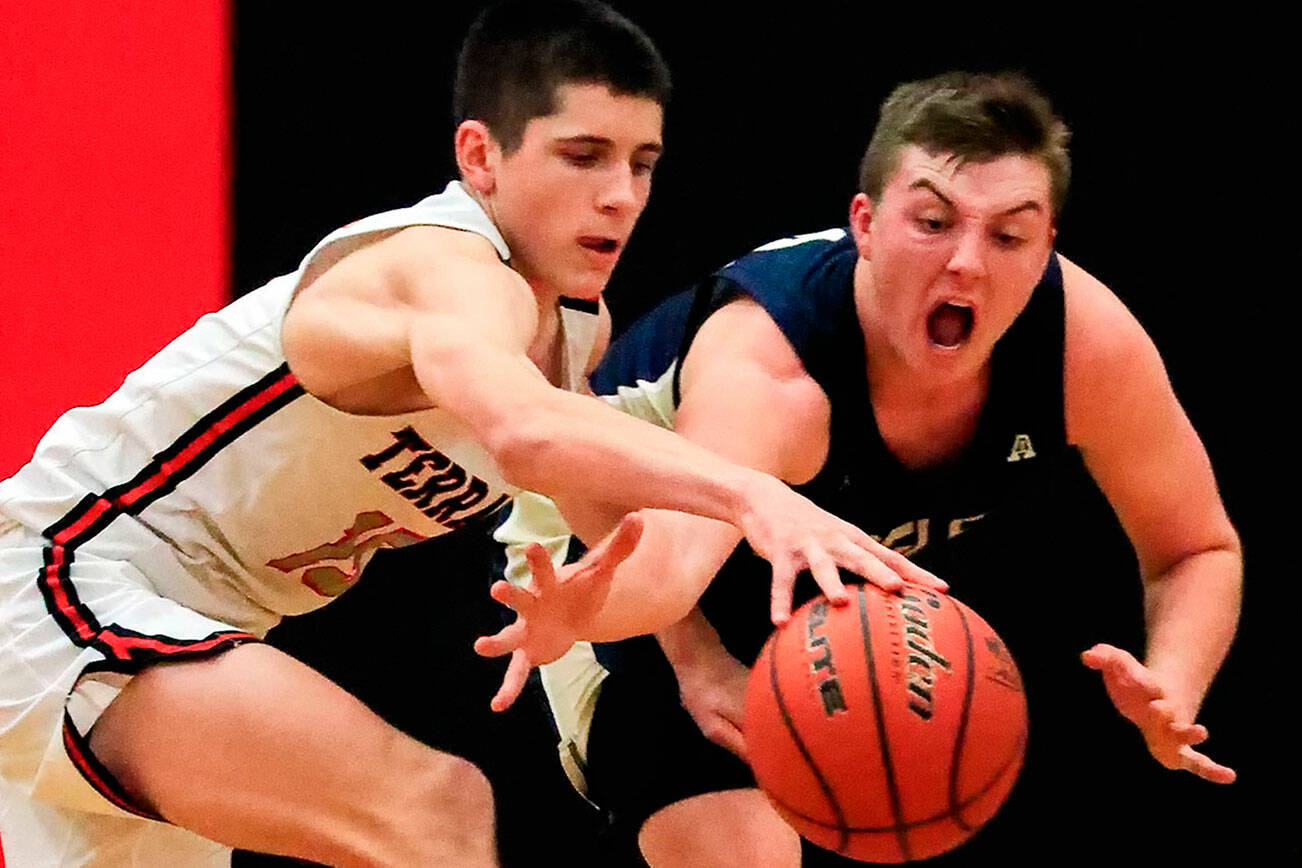 Mountlake Terrace's Jaxon Dubiel, left, and Arlington's Ethan Martin chase down a loose ball Friday evening at Mountlake Terrace High School on December 10, 2021. The Eagles won 70-55. (Kevin Clark / The Herald)