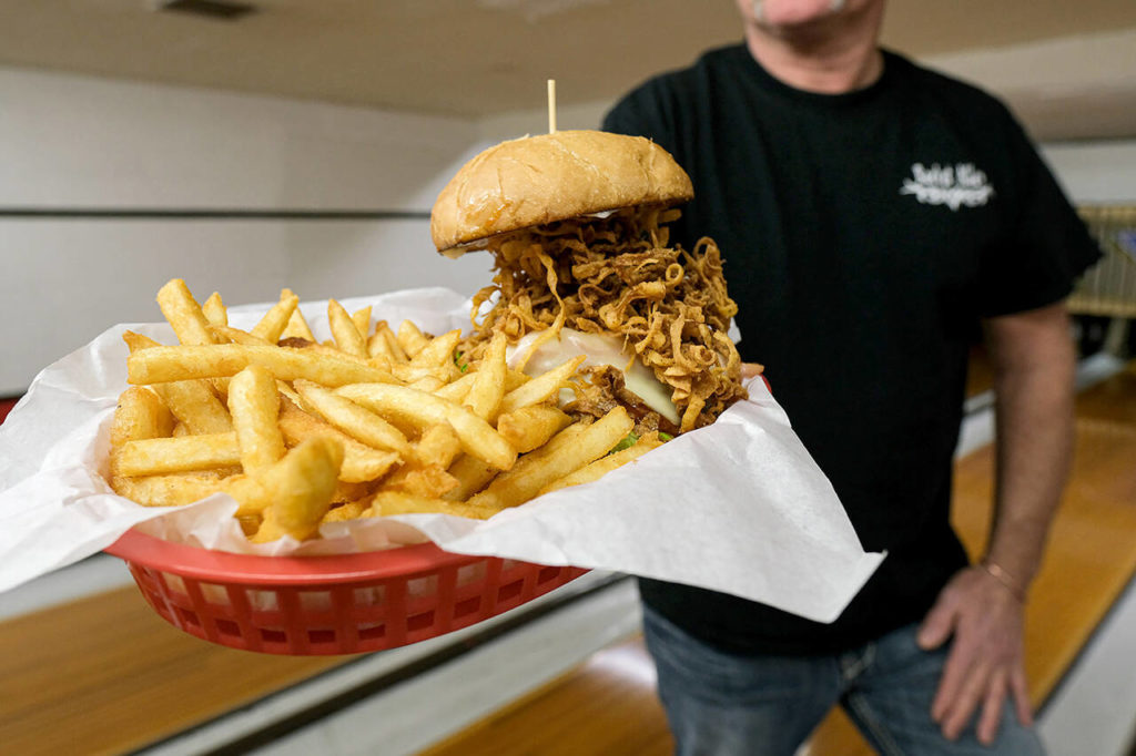 Rocket Alley’s award-winning Western BBQ burger ($16) is topped with thinly shaved ham, Swiss cheese, spicy barbecue sauce, mayo and the real treat: a cascade of crispy deep-fried onions. (Taylor Goebel / The Herald)
