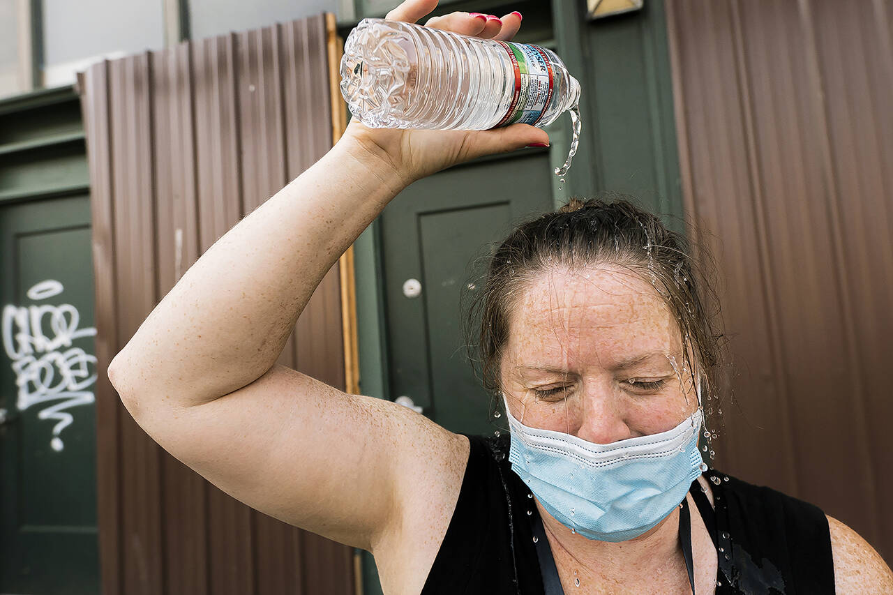 Darlene McApline, an administrative coordinator with Cascadia Behavioral Healthcare’s street outreach team, dumps a bottle of water on her head to cool off while loading supplies on Aug. 12, 2021, in Portland, Oregon. (AP Photo/Nathan Howard, file)