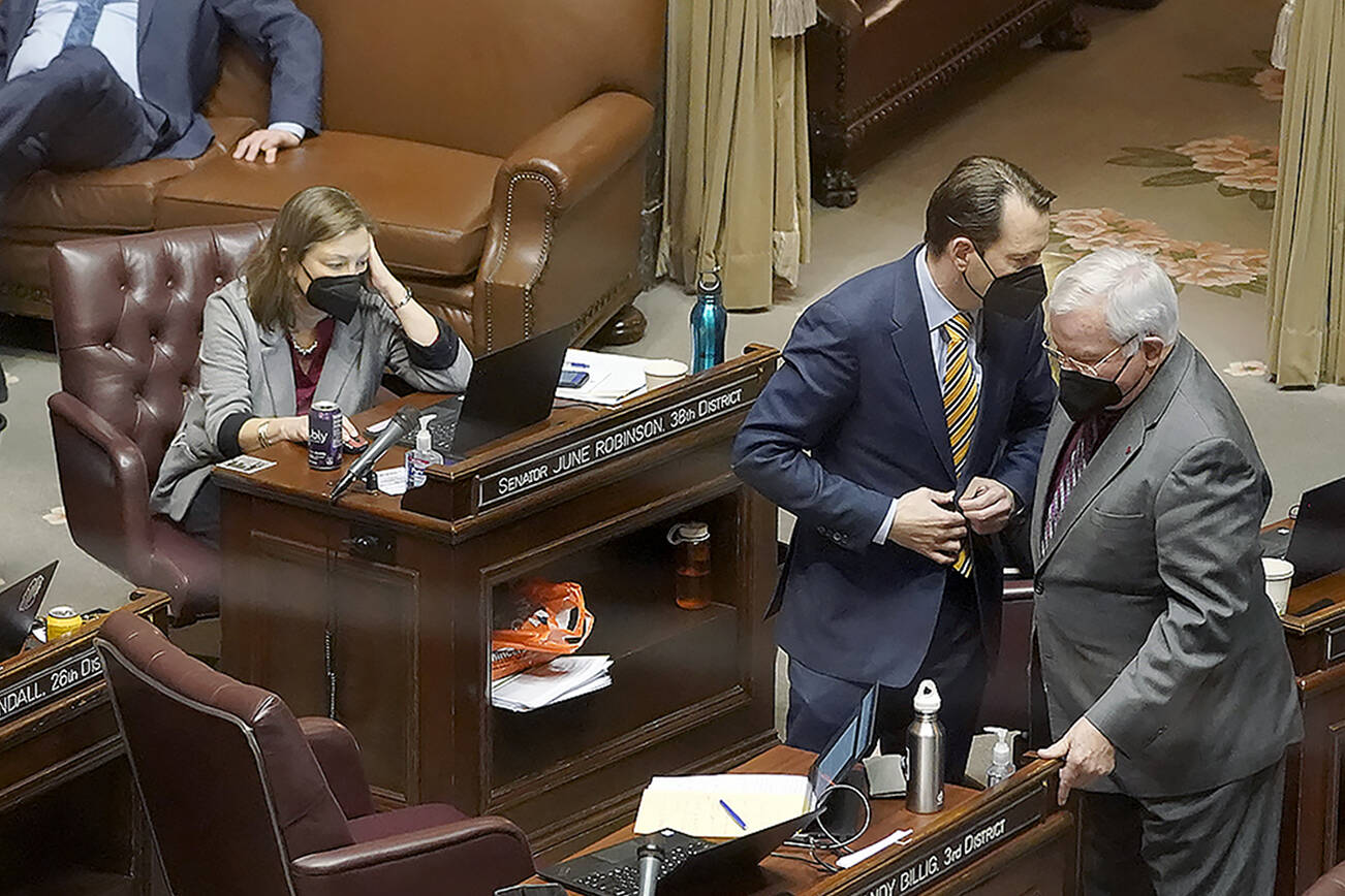 Sen. Andy Billig (D-Spokane), second from right, confers with Sen. Sam Hunt, D-Olympia, right, in front of Sen. June Robinson's, D-Everett, desk on the Senate floor at the Capitol in Olympia, Wash., on Tuesday, Feb. 15, 2022, during debate over a measure that authorizes legislative leaders to terminate any state of emergency called by the governor after 90 days if the Legislature is not in session. The measure passed the Democratic-led Senate chamber and now heads to the House, also held by Democrats, for consideration. (AP Photo/Ted S. Warren)