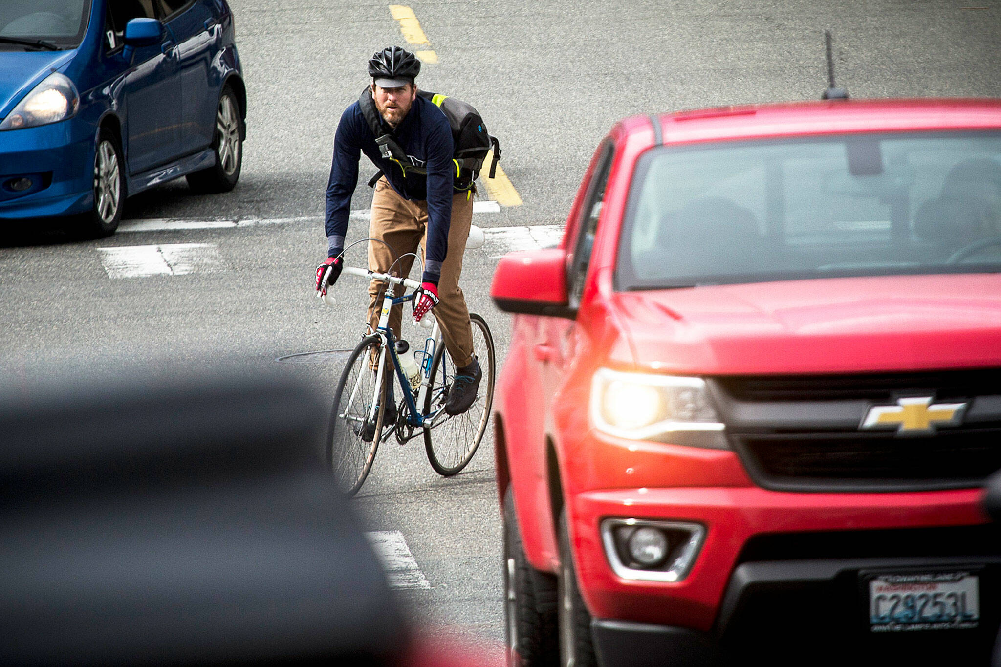 Warland Hewitt Wight rides through traffic in Everett in March, 2018. Included in a transportation package state lawmakers are considering is $300 million for bicycle and pedestrian projects across the state. (Ian Terry / Herald file photo)