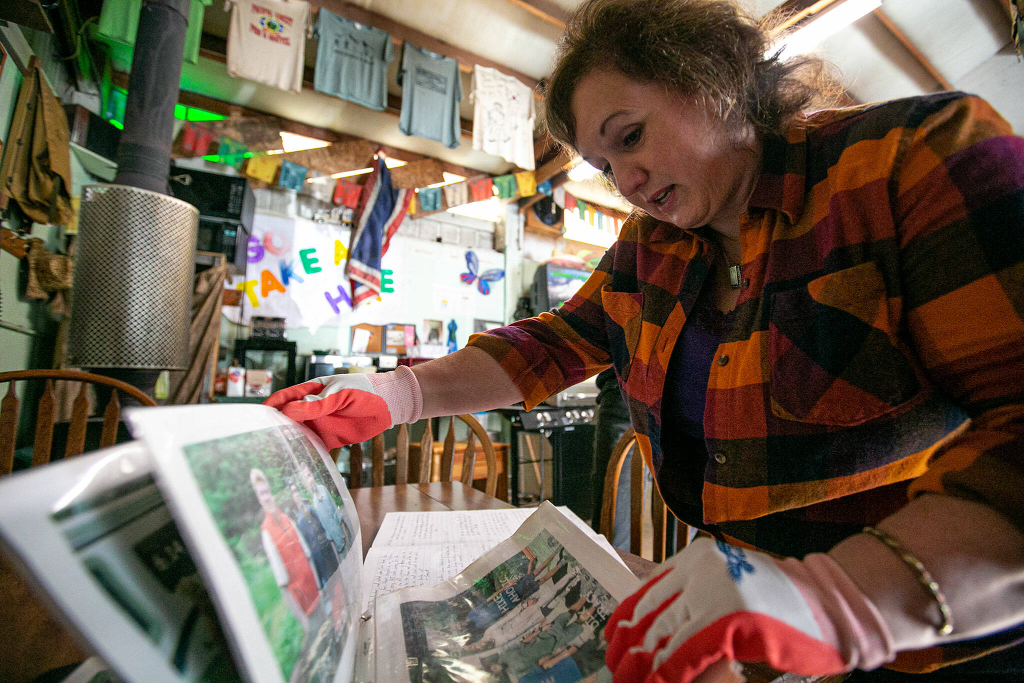 Diane Altman Jennings combs through a photo book of her father’s life in Baring. (Ryan Berry / The Herald)