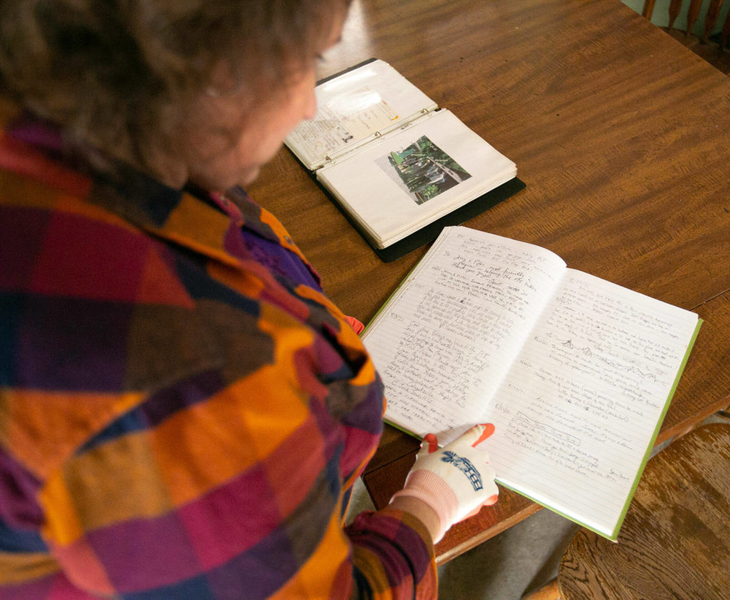 Diane Altman Jennings reads through a logbook filled with notes from hikers who stayed at the Dinsmores’ Hiker Haven over the years. (Ryan Berry / The Herald) 
