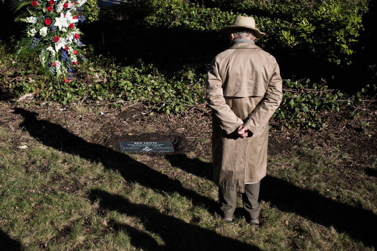 David Campron stands to read the newly placed grave stone for Ben Lewis at the Evergreen Cemetery on Wednesday, Feb. 23, 2022 in Everett, Wa. (Olivia Vanni / The Herald)