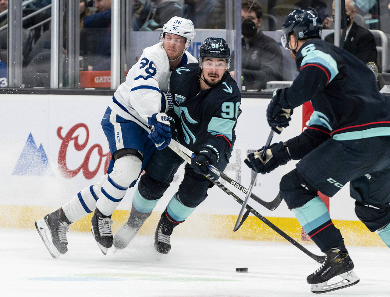 Seattle Kraken left wing Marcus Johansson (center) and Toronto Maple Leafs defenseman Rasmus Sandin (left) collide while fighting for the puck during the first period of a game Monday in Seattle. (AP Photo/Stephen Brashear)