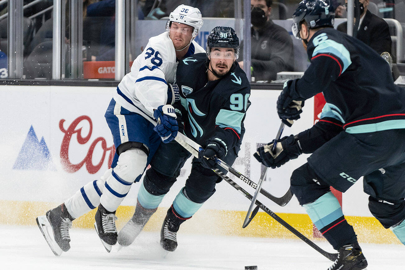 Seattle Kraken left wing Marcus Johansson, center, and Toronto Maple Leafs defenseman Rasmus Sandin, left, collide while fighting for the puck during the first period of an NHL hockey game, Monday, Feb. 14, 2022, in Seattle. (AP Photo/Stephen Brashear)