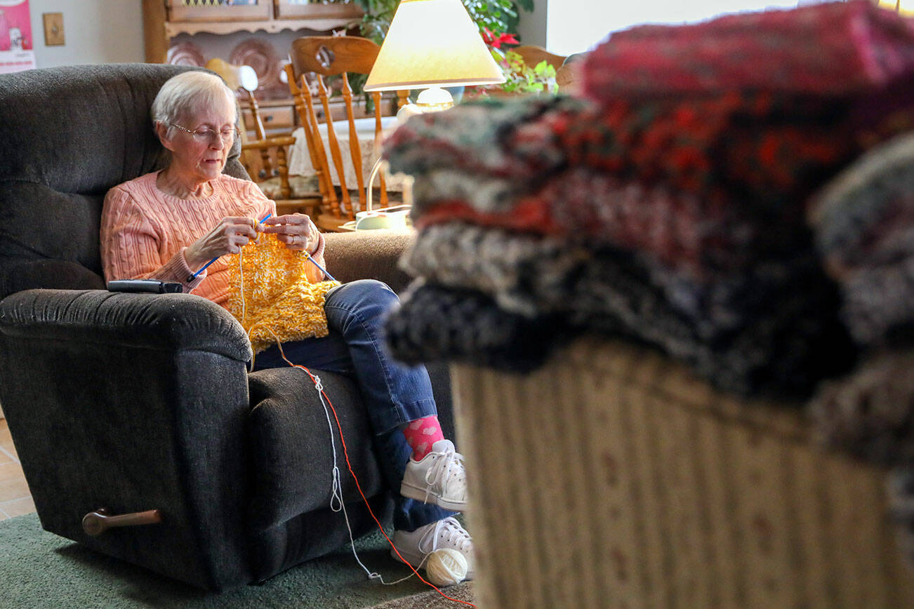 Vicki Wahl knits scarves at her home in Lake Stevens, Washington on February 17, 2022. More than 170 of her scarves will be handed out during this years’ homelessness count.  (Kevin Clark / The Herald )
