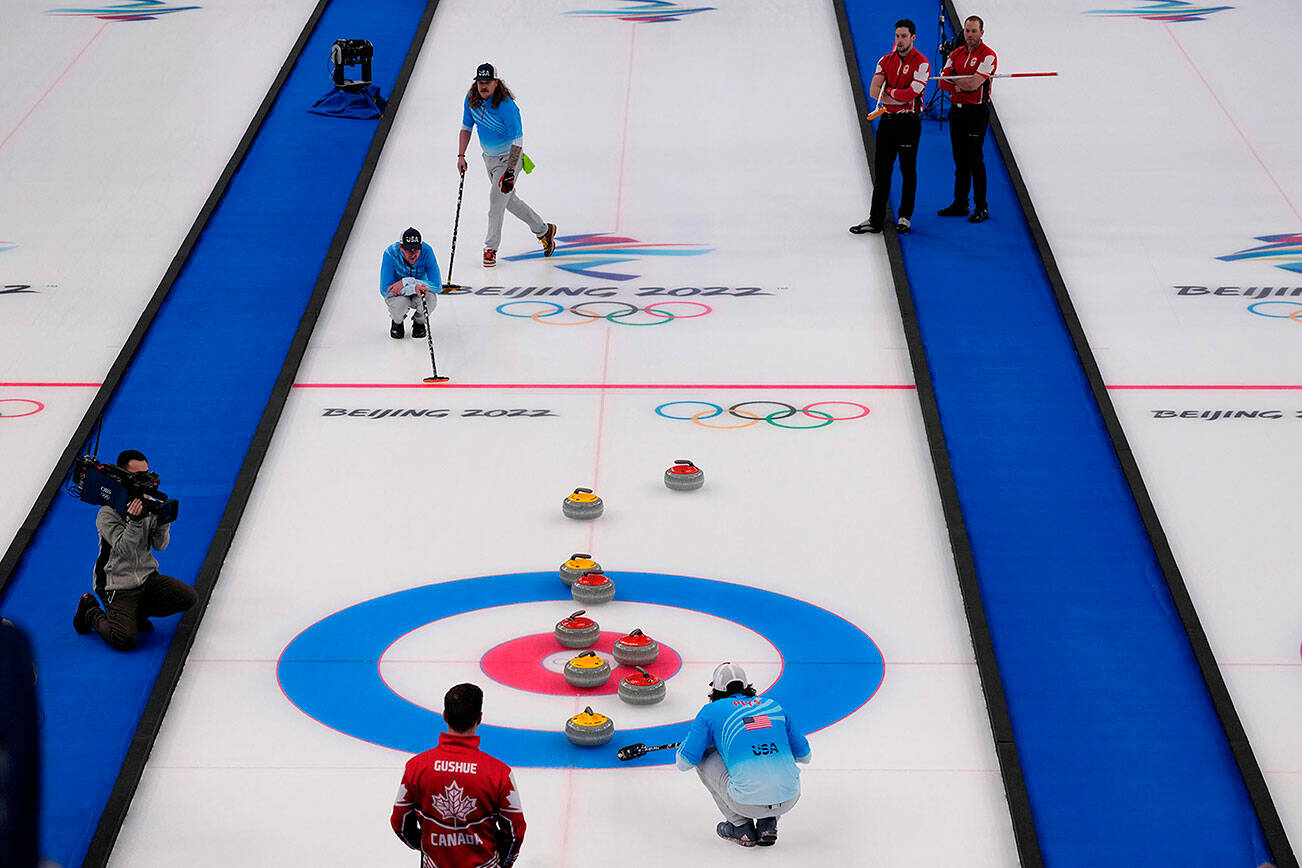 Players watch a rock approach the button during the men's curling bronze medal match between Canada and the United States at the Beijing Winter Olympics Friday, Feb. 18, 2022, in Beijing. (AP Photo/Nariman El-Mofty)