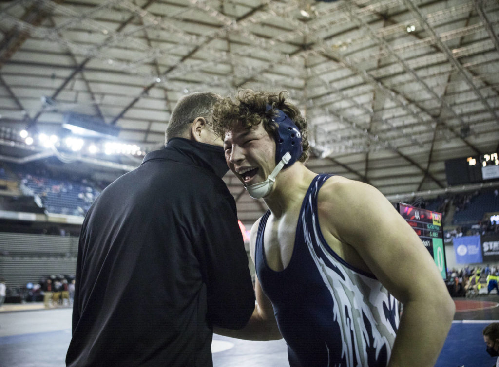 Glaicer Peak’s Jacob Erickson hugs a coach after winning the 4A 220-pound championship match at the Mat Classic XXXIII on Saturday in Tacoma. (Olivia Vanni / The Herald)
