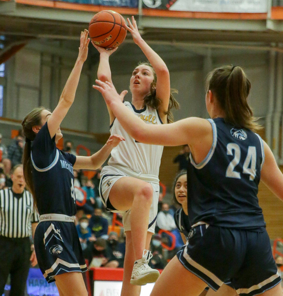 Everett’s Emma Larson pulls up for a floater with Meadowdale’s Jordan Leith, left, and Ava Powell defending Saturday afternoon at during the 3A District Tournament at Everett Community College in Everett, Washington on February 19, 2022. (Kevin Clark / The Herald )
