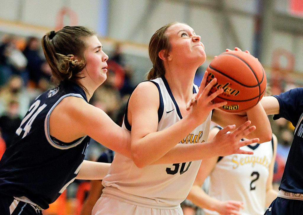 Everett’s Caroline Jameson looks to score with Meadowdale’s Ava Powell reaching in Saturday afternoon at during the 3A District Tournament at Everett Community College in Everett, Washington on February 19, 2022. (Kevin Clark / The Herald )
