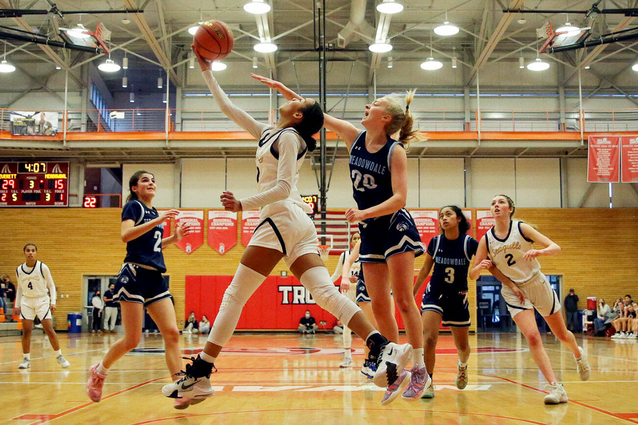 Everett’s Alana Washington attempts an underhand layup with Meadowdale’s McKenna Kuecker trailing Saturday afternoon at during the 3A District Tournament at Everett Community College in Everett, Washington on February 19, 2022. (Kevin Clark / The Herald )