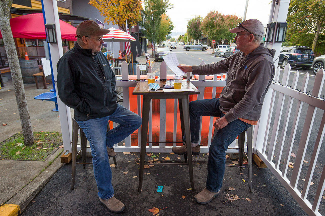 Scott McEntire and Jim Coe enjoy a drink and lunch in an outdoor seating tent at the Salish Sea Brewing Co. along Dayton Street on Monday, Oct. 12, 2020 in Edmonds, Washington.  (Andy Bronson / The Herald)