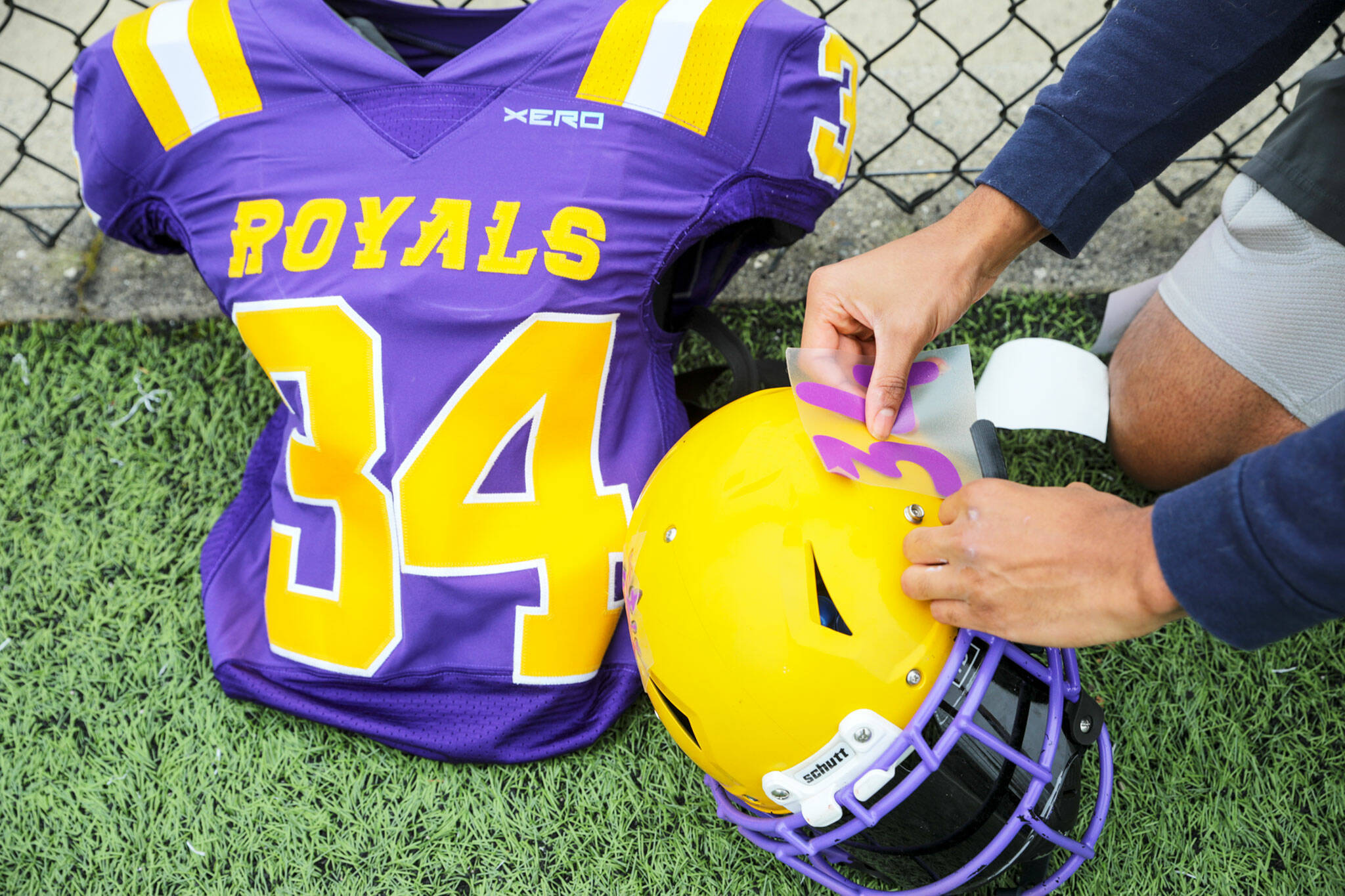 A numbers decal is applied to a Royals helmet before the first game of the season at Archbishop Murphy High School in Everett. (Kevin Clark / The Herald)