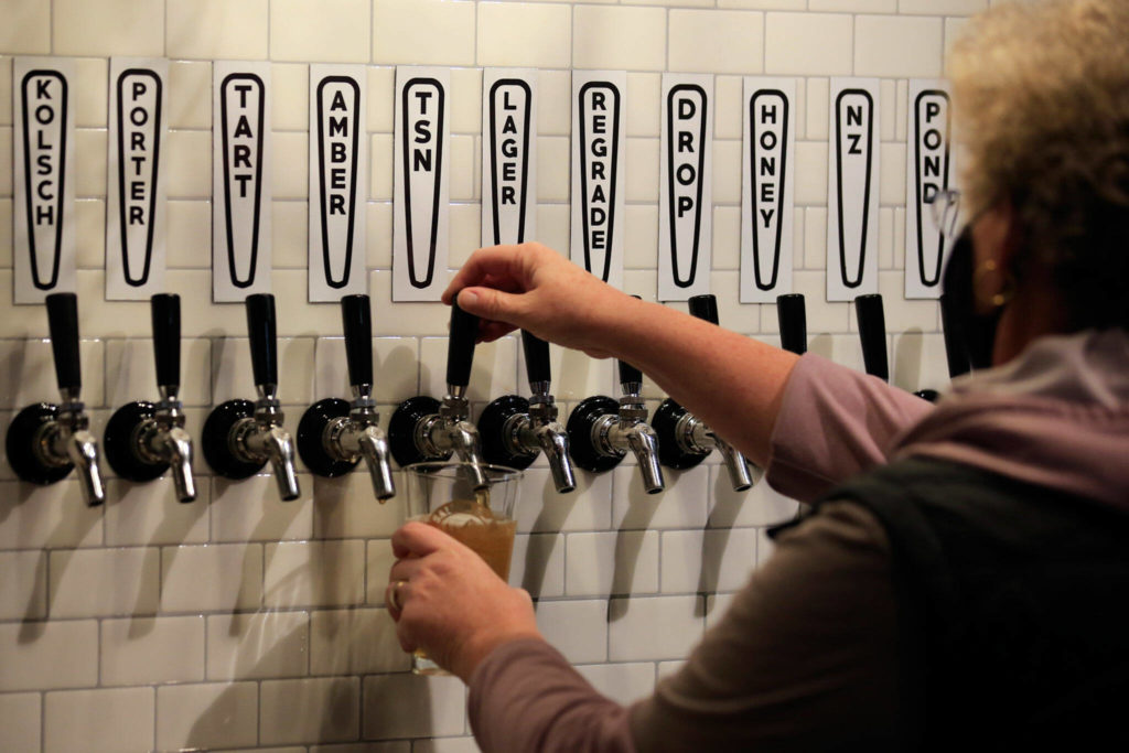 A Salish Sea Brewing employee draws a beer at The Boathouse on Nov. 24. (Kevin Clark / The Herald)
