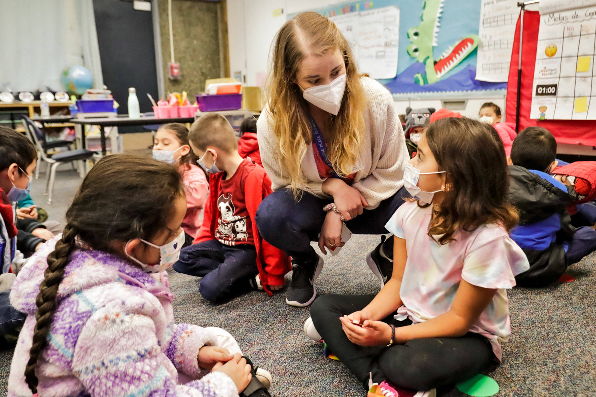 Teacher Erika Rabura talks to Isabella Bauta (right) and Pilar Garcia (left) at College Place Elementary School in Lynnwood. (Kevin Clark / The Herald)