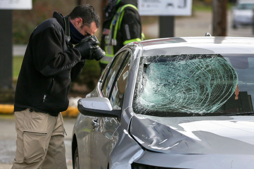 A Washington State Patrol detective photographs a vehicle involved in a hit-and-run double fatality in Bothell on Feb. 19, 2021. (Kevin Clark / Herald file)
