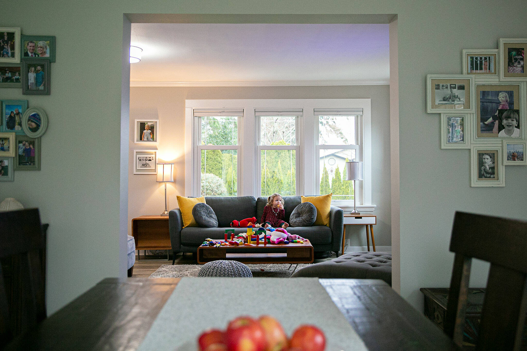 Aya Zebari, 2, the granddaughter of reporter Andrea Brown, snacks on an ice cream cone in the living room of the recently renovated 100-year-old bungalow in Everett. The yellow pillows on the couch are a homage to the home’s former bright yellow exterior. (Ryan Berry / The Herald)