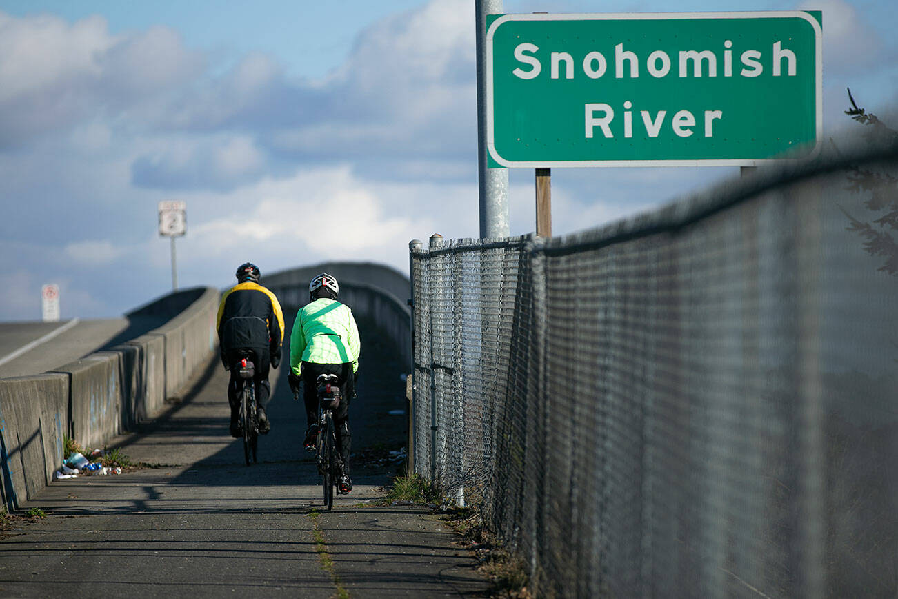 Two cyclists head eastbound along the Highway 2 trestle path Saturday, March 5, 2022, in Everett, Washington. (Ryan Berry / The Herald)