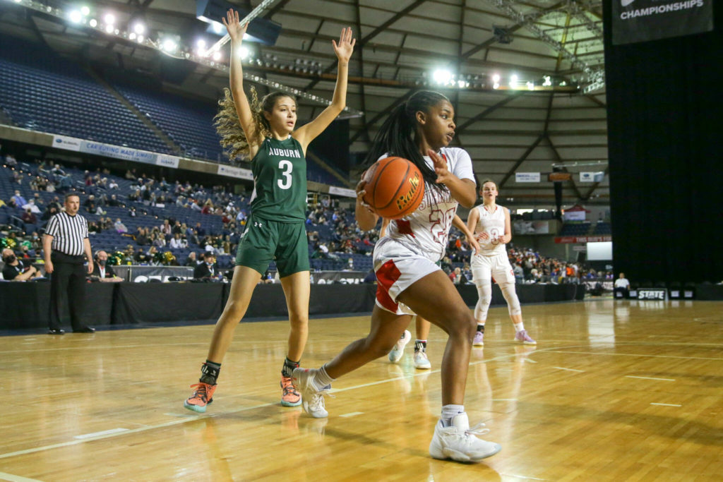 Stanwood’s Chloe Santeford looks to pass along the baseline with Auburn’s Jaylah Brown trailing Wednesday evening in Tacoma. The Spartans advance with their 53-39 victory over the Trojans. (Kevin Clark / The Herald)
