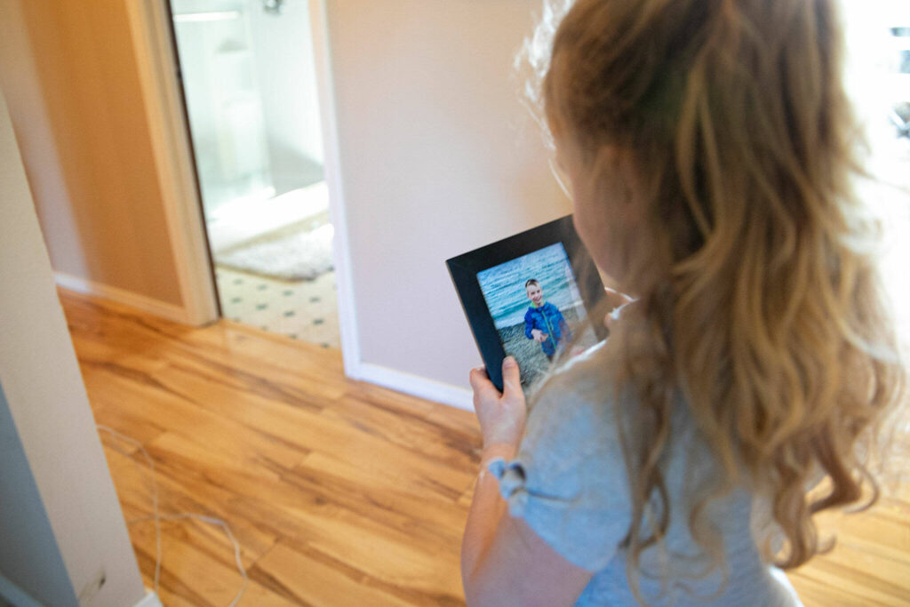 Emalyn Page, 5, walks through the house with a photo of Mykyta —as she often does, according to her mother — on Sunday in Snohomish. (Ryan Berry / The Herald)
