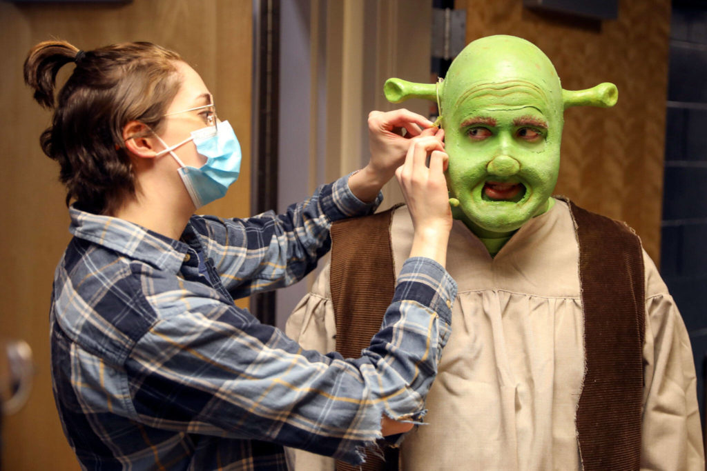 RJ Stevensonn (left) removes a microphone from Will Litton during a dress rehearsal of Shrek the Musical at Byrnes Performing Arts Center in Arlington on Feb. 26. Final performances by Arlington High School students are March 11 at 7 p.m. and March 12 at 1 p.m. and 7 p.m (Kevin Clark / The Herald)
