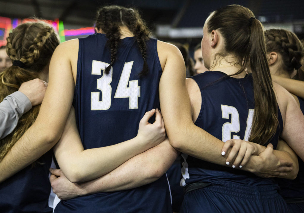 Arlington players link arms during a huddle before the start of the 3A state semifinal at the Tacoma Dome on Friday, March 4, 2022. (Olivia Vanni / The Herald)
