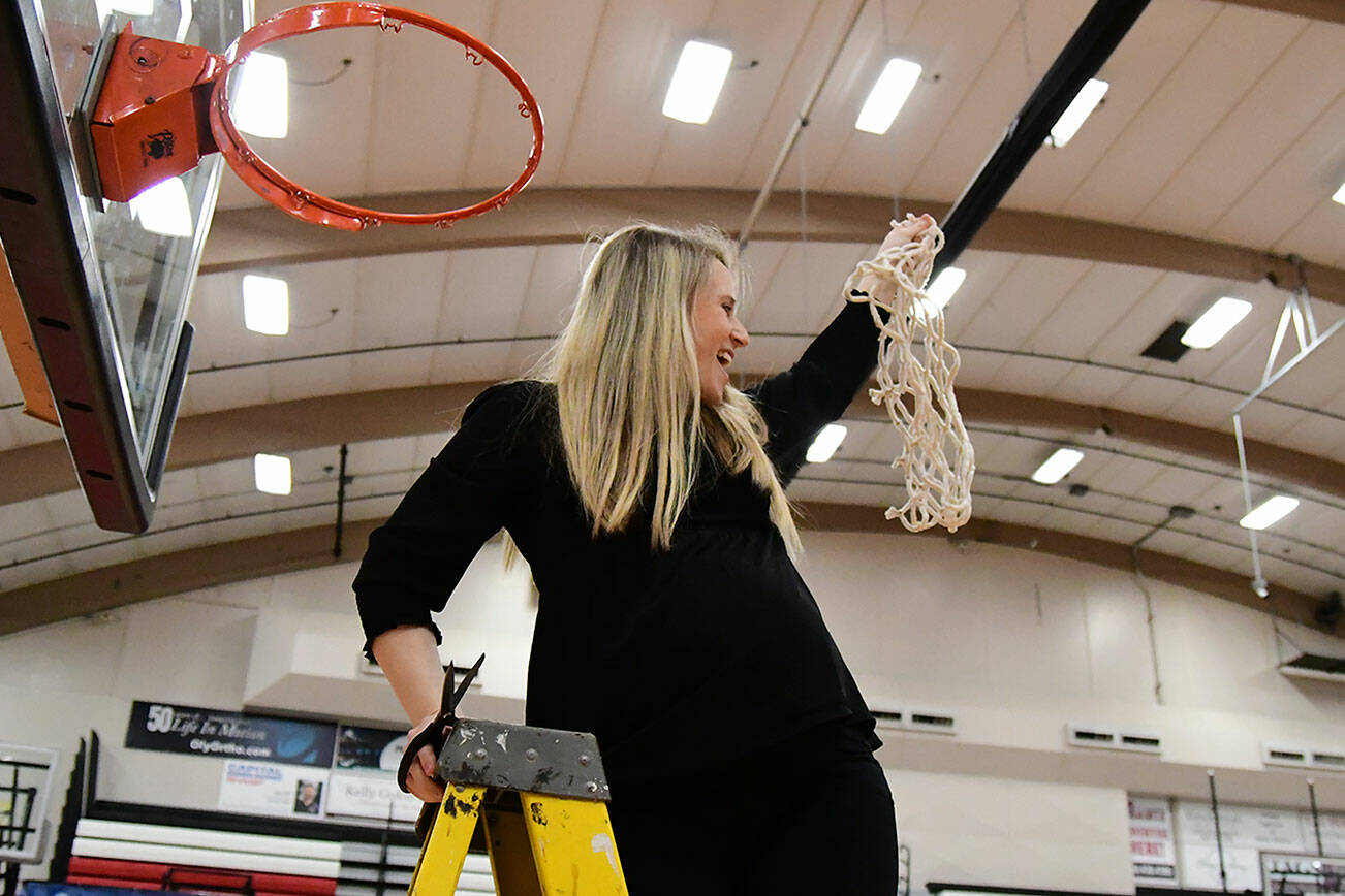 Randi Richardson-Thornley, an Arlington High School grad who coaches the Central Washington University women's basketball team, holds a net in the air in celebration after CWU won its first-ever GNAC tournament title Saturday, March 5, 2022, in Lacey. (Ron Smith)