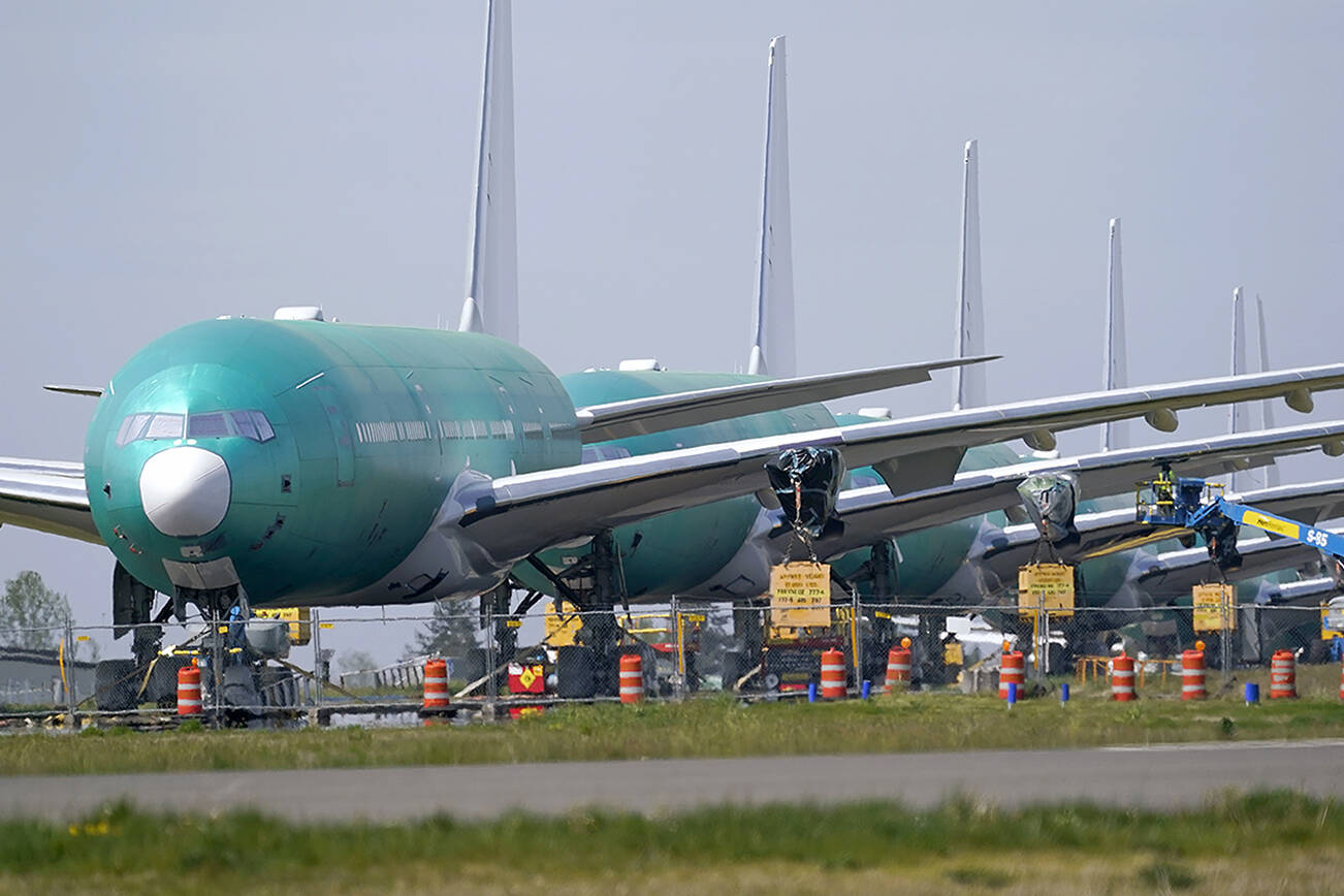 FILE - A line of Boeing 777X jets are parked nose to tail on an unused runway at Paine Field, near Boeing's massive production facility, Friday, April 23, 2021, in Everett, Wash.  After a couple dismal years, Boeing is getting more orders and delivering more airline planes. The company said Tuesday, Jan. 11, 2022, that it delivered 38 commercial planes in December and 340 for all of 2021.  (AP Photo/Elaine Thompson, File)