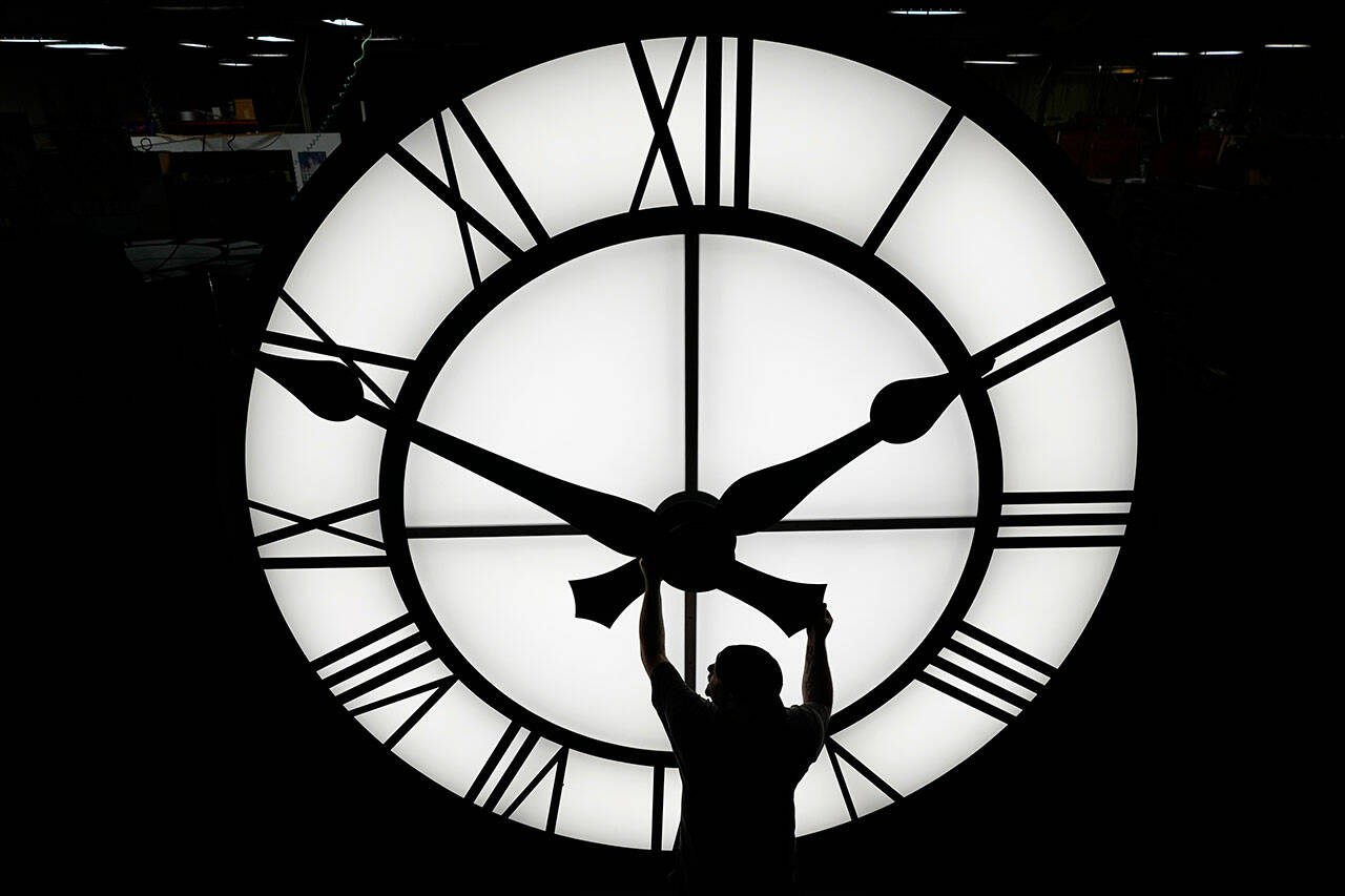 Electric Time technician Dan LaMoore adjusts a clock hand on a 1,000-pound, 12-foot diameter clock constructed for a resort in Vietnam, March 9, 2021, in Medfield, Mass. (Elise Amendola / Associated Press)