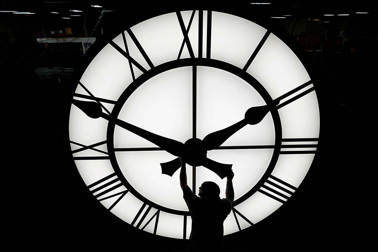 Electric Time technician Dan LaMoore adjusts a clock hand on a 1000-lb., 12-foot diameter clock constructed for a resort in Vietnam, Tuesday, March 9, 2021, in Medfield, Mass. Daylight saving time begins at 2 a.m. local time Sunday, March 14, 2021, when clocks are set ahead one hour. (AP Photo/Elise Amendola)