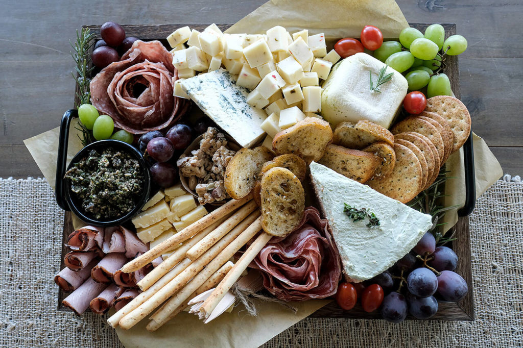 Savory salami cheesecake, layered pesto torte, award-winning olive tapenade, fresh fruit, crostini and more cover Charcuterie by Stephanie’s bountiful boards. (Taylor Goebel / The Herald)
