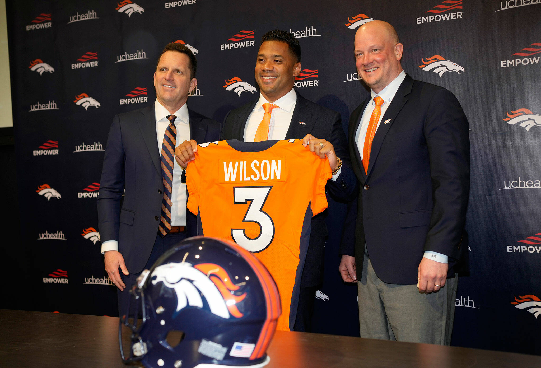 New Broncos quarterback Russell Wilson (center) holds up his jersey while flanked by head coach Nathaniel Hackett (right) and general manager George Paton after a news conference Wednesday in Englewood, Colo. (AP Photo/David Zalubowski)