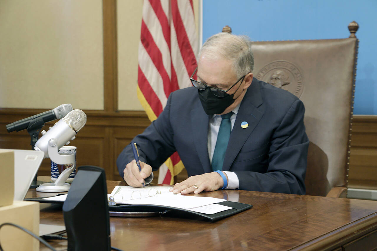 Washington Gov. Jay Inslee signs a measure that prohibits legal action against both people seeking an abortion and those who aid them, on Thursday in Olympia. (AP Photo/Rachel La Corte)