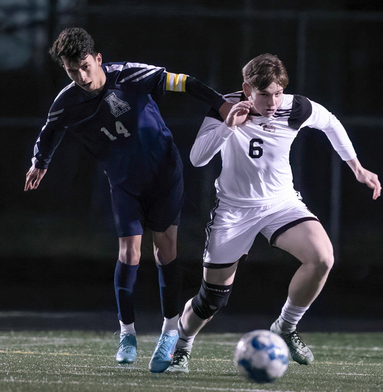 Arlington’s Emmanuel Escalante, left, and Monroe’s Owen Skurdal chase down the ball Friday evening at Arlington High School in Arlington, Washington on March 18, 2022. (Kevin Clark / The Herald)